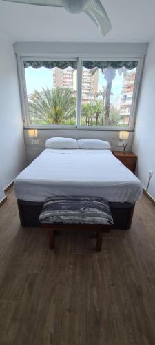 Bett in einem Zimmer mit einem großen Fenster in der Unterkunft San Juan Live in Alicante