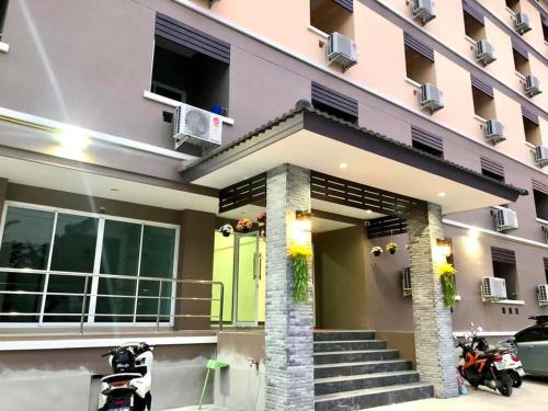 een huis met een groene deur en een gebouw bij MY HOME Hotel - Phutthamonthon 4 Road, near Mahidol University Salaya in Ban Krathum Lom