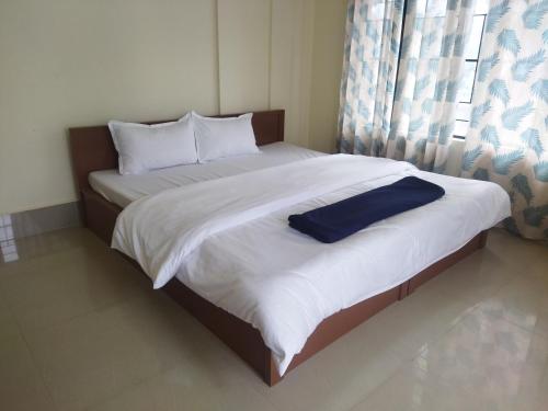 a bedroom with a large bed with white sheets and blue pillows at HEEMSTEDE in Shillong