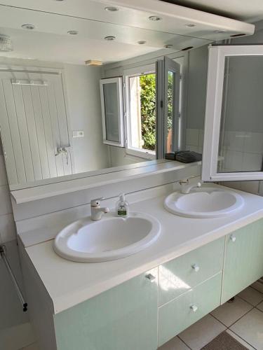 une salle de bain avec deux lavabos et un grand miroir dans l'établissement La plage au bout du jardin / Sword Beach cottage, à Hermanville-sur-Mer