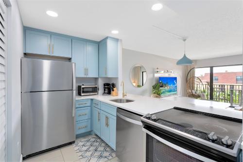 eine Küche mit blauen Schränken und einem Kühlschrank aus Edelstahl in der Unterkunft Chateau by the Sea in Cocoa Beach