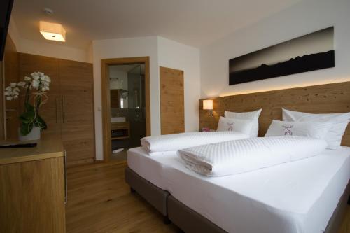 a bedroom with a large bed with white sheets at Berglife Appartements in Serfaus
