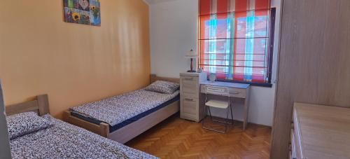 um quarto com 2 camas, uma secretária e uma janela em DLX Apartman Adriatics em Herceg Novi