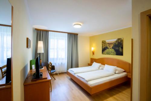 Habitación de hotel con cama y TV en Weinberghof Ilkerl-Luf, en Krems an der Donau