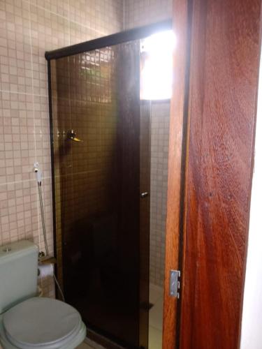 a bathroom with a toilet and a glass shower door at Pousada Nova Conquista in Penedo