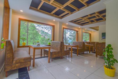 a dining room with chairs and tables and windows at Hotel The Paal in Shimla