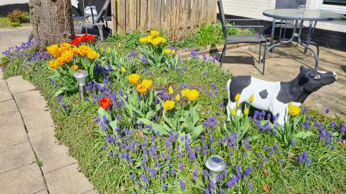 a garden with a cow statue in the middle of flowers at Roos Guesthouse Holiday Appartements in Valkenburg