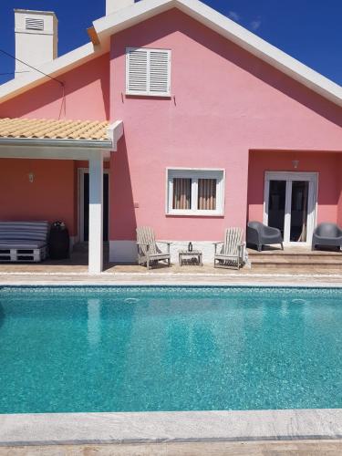 a pink house with a swimming pool in front of it at Family Villa Pool & Beach in Caparica