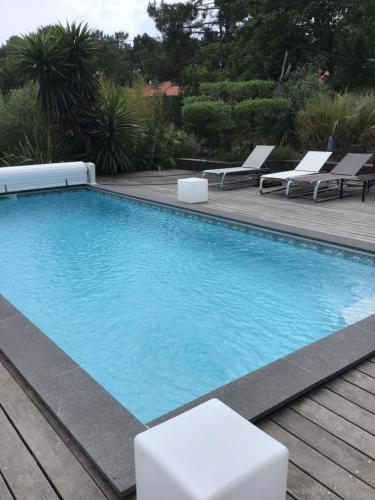 - une piscine avec une terrasse et des chaises longues dans l'établissement Agréable appartement à 1km du centre de La Teste-de-Buch, à La Teste-de-Buch