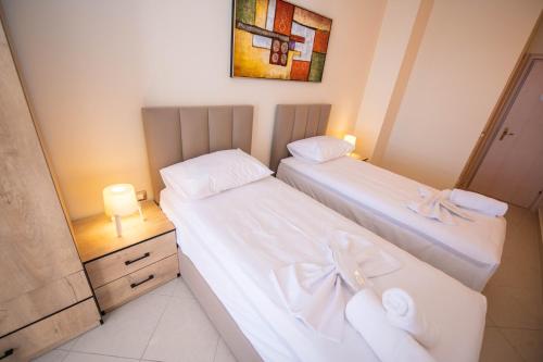 two beds in a small room with a mirror at Hotel Zanzi in Durrës
