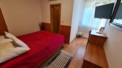 a bedroom with a red bed and a flat screen tv at SOBE/ROOMS RIVA in Zadar