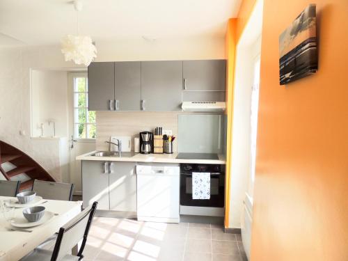 cocina con armarios grises, mesa, mesa y sillas en Le Gîte du Petit Plessis, en Saint-Viaud