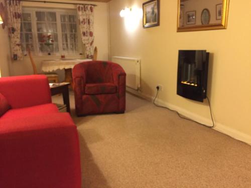 a living room with a red chair and a fireplace at Spacious family & dog friendly home from home with sea views and private garden in Porlock