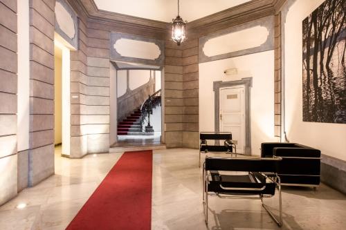 a hallway with chairs and a red rug at Moncada Suites & Apartments in Palermo