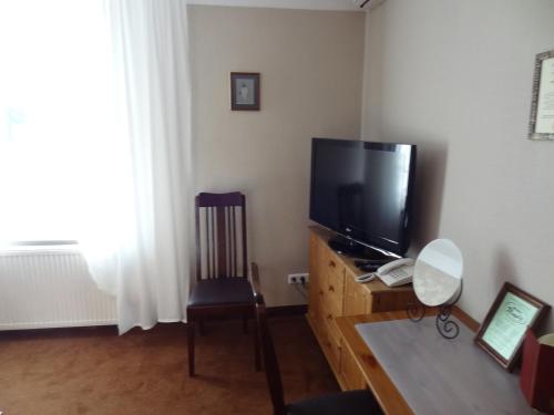 a living room with a flat screen tv and a chair at Pensjonat U Kota Wasyla in Chodzież