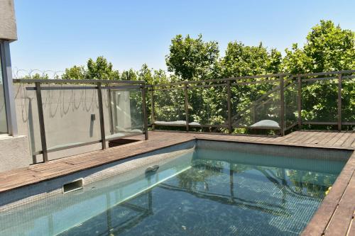 una piscina con terrazza in legno accanto a una casa di Syrah Suites a Buenos Aires
