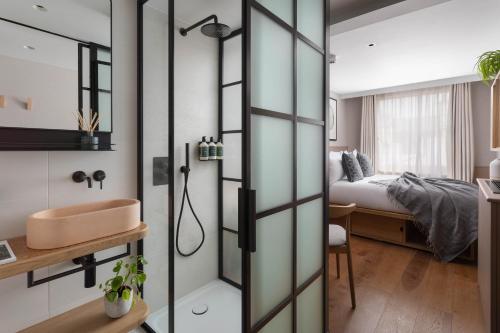a bathroom with a bed, shower, and a window at Inhabit, Queen's Gardens in London