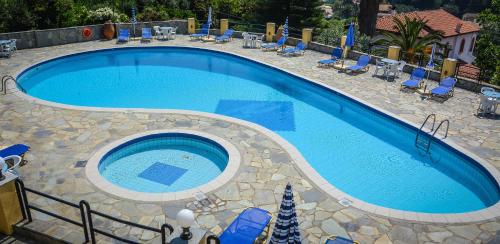 a large swimming pool with blue lounge chairs and sidx sidx sidx at Penelope Apartment Hotel in Dassia