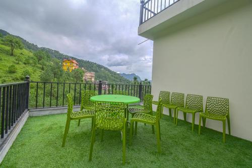 a green table and chairs on a balcony at Hotel The Paal in Shimla