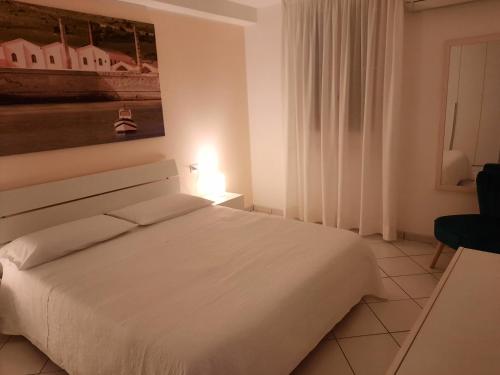 a bedroom with a white bed and a painting on the wall at Villa Oblò in Favignana