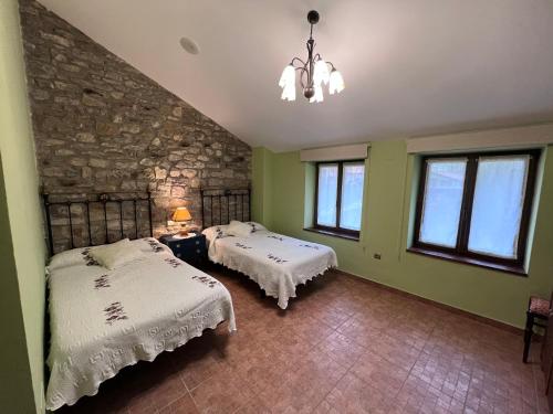 a bedroom with two beds and a stone wall at La Casina Del Rio in Argovejo