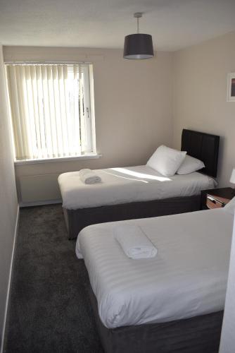 a hotel room with two beds and a window at Kelpies Serviced Apartments- Abbotsford in Falkirk