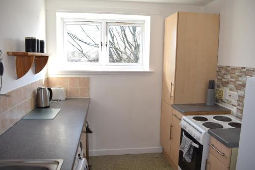 a kitchen with a stove and a window at Kelpies Serviced Apartments- Abbotsford in Falkirk