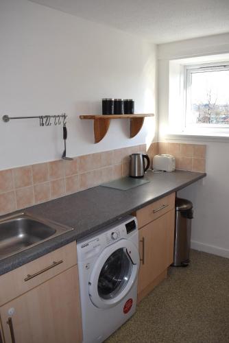 a kitchen with a washing machine and a sink at Kelpies Serviced Apartments- Abbotsford in Falkirk