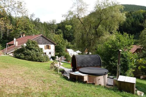 a backyard with a grill and a table in the grass at La petite ferme in La Chapelle