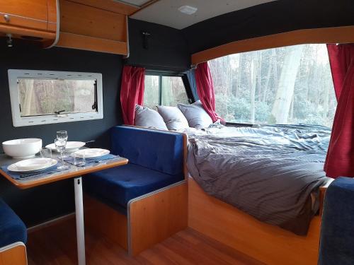 Kromven On Wheels في Merksplas: غرفة نوم مع سرير وطاولة في مقطورة