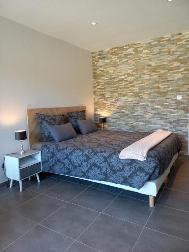 a bedroom with a bed and a brick wall at Le Studio Restauration Netflix et Jacuzzi Proche des grands lacs in Montmorency-Beaufort