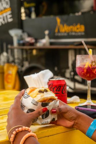 a person is holding a sandwich on a table at Gran Hotel Stella Maris Urban Resort & Conventions in Salvador