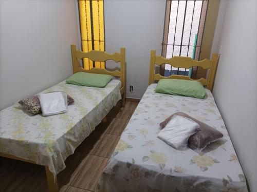 two beds in a room with two windows at Pousada Bem Viver 1 in Itaperuna