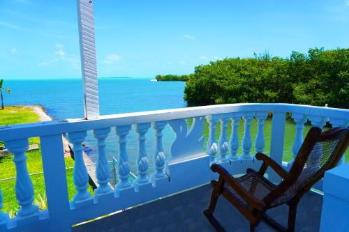una sedia su un balcone con vista sull'oceano di See Belize WATERSIDE Sea View Suite with Infinity Pool & Overwater Deck a Belize City