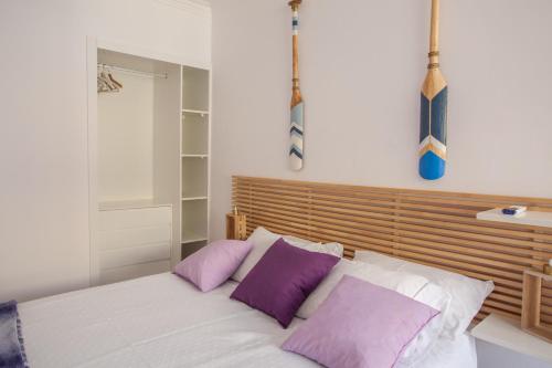 um quarto com uma cama com almofadas roxas e brancas em Sea, Surf & The City-RENOVATED APRIL 2022 em Costa da Caparica