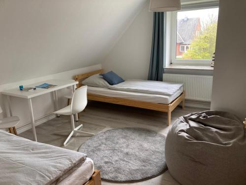 a bedroom with a bed and a desk and a window at Ferienhaus Tidenkieker in Nordstrand
