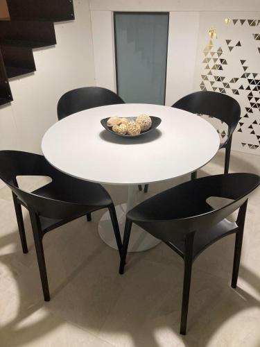 una mesa blanca con sillas negras y un plato de comida en A 20 Passi... en Rocca Imperiale