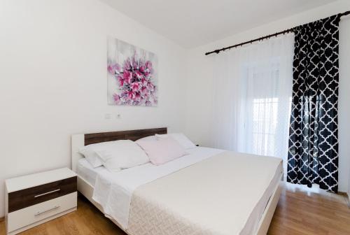 a white bedroom with a large bed and a window at Apartment Marica in Lopar