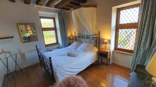 a bedroom with a bed with white sheets and two windows at Château de Jallanges & Spa à Vouvray - 1h de spa incluse par jour in Vouvray