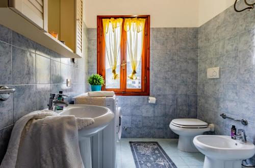 a bathroom with a sink and a toilet and a window at Trilocale Ricky Marina di Campo in Campo nell'Elba