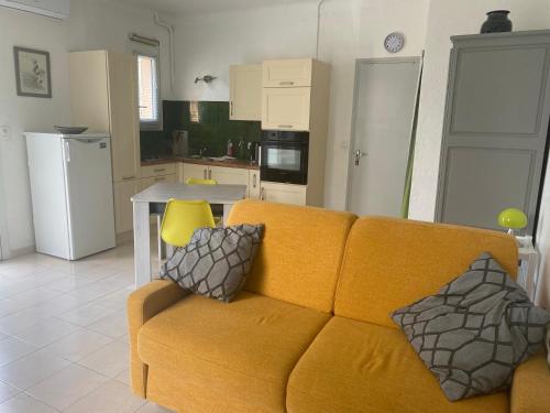 uma sala de estar com um sofá amarelo e uma cozinha em Joli studio avec parking à 2 min à pied de la plage em Argelès-sur-Mer