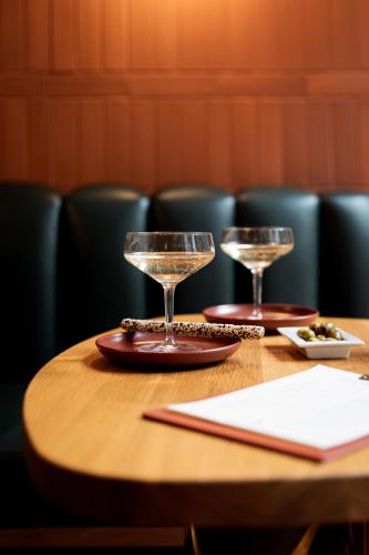 a wooden table with two wine glasses on it at Hôtel AMI - Orso Hotels in Paris