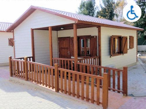 a small house with a wooden fence and a porch at Camping Los Llanos in Denia
