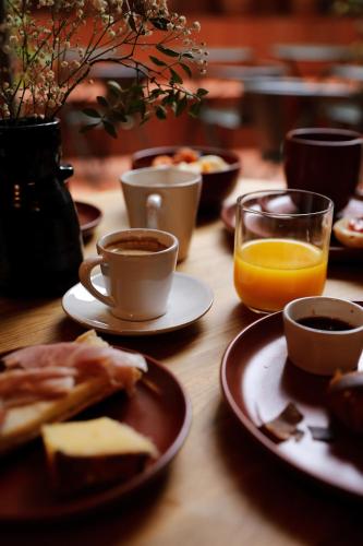 a table with plates of food and cups of coffee and orange juice at Hôtel AMI - Orso Hotels in Paris