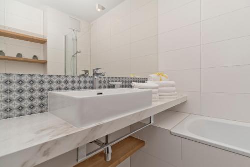 a white bathroom with a sink and a mirror at Aparthotel Anchoria BlueApart in Mechelinki