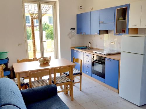 cocina con armarios azules, mesa, mesa y sillas en Villa Gabriella, en Patti