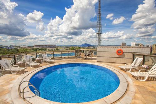 a swimming pool on the roof of a building with chairs and a patio at Brasil 21 Convention Affiliated by Meliá in Brasilia