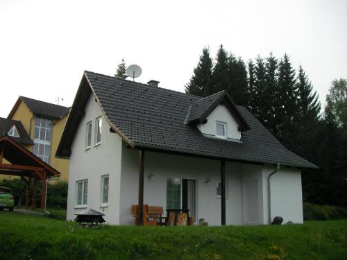 een wit huis met een zwart dak bij Dům na Lipně in Lipno nad Vltavou