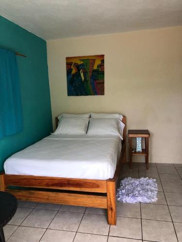 a bedroom with a bed with a white sheets and a table at Sunshine Hotel Little Corn Island in Little Corn Island