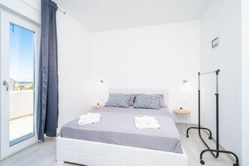 a white bedroom with a bed and a large window at Apartment Olive in Dubrovnik